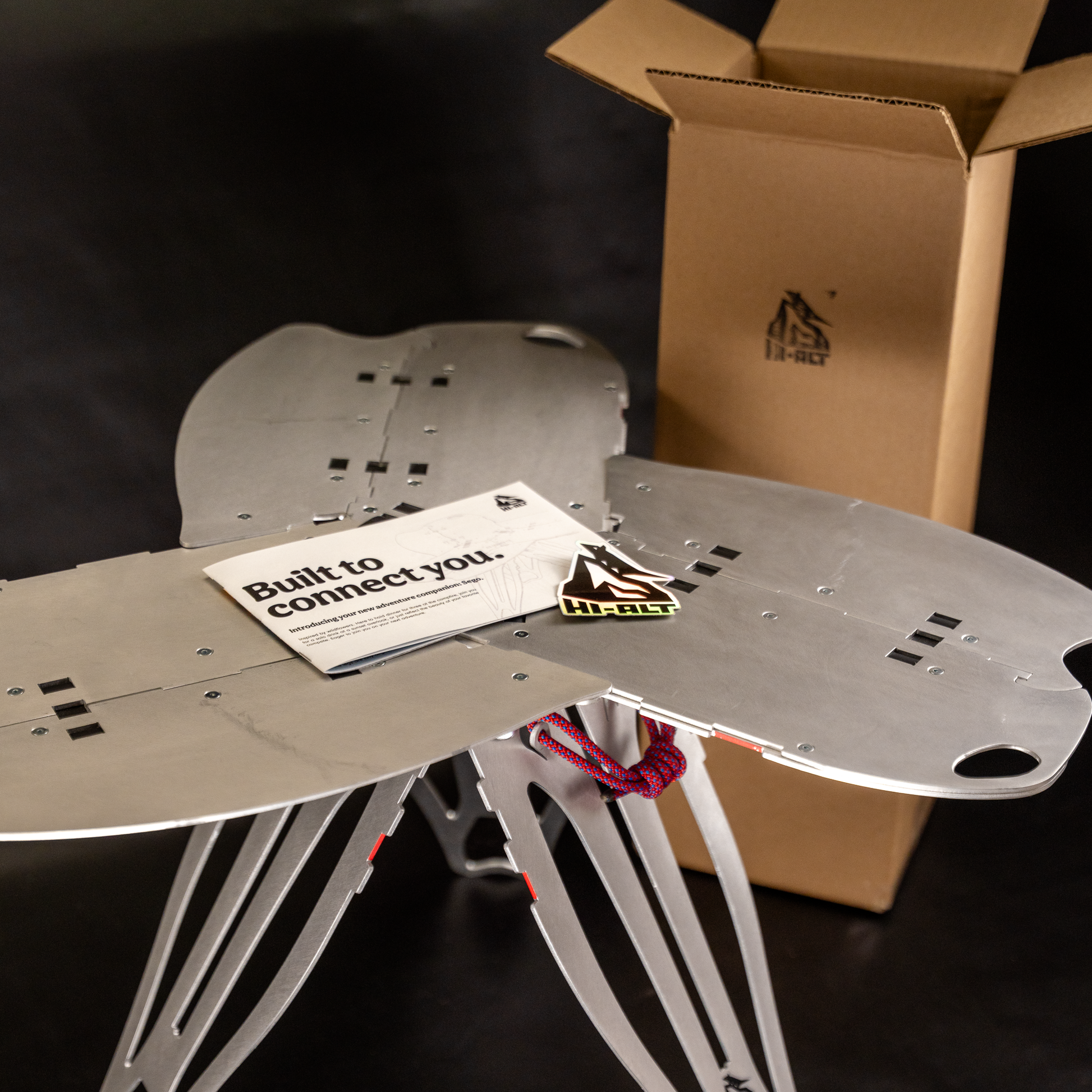 Sego with the user manual, an included sticker, and the recycled shipping box in the background.